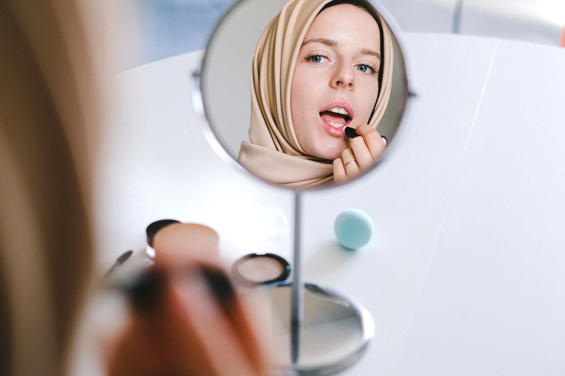 A woman applying makeup in front of a mirror