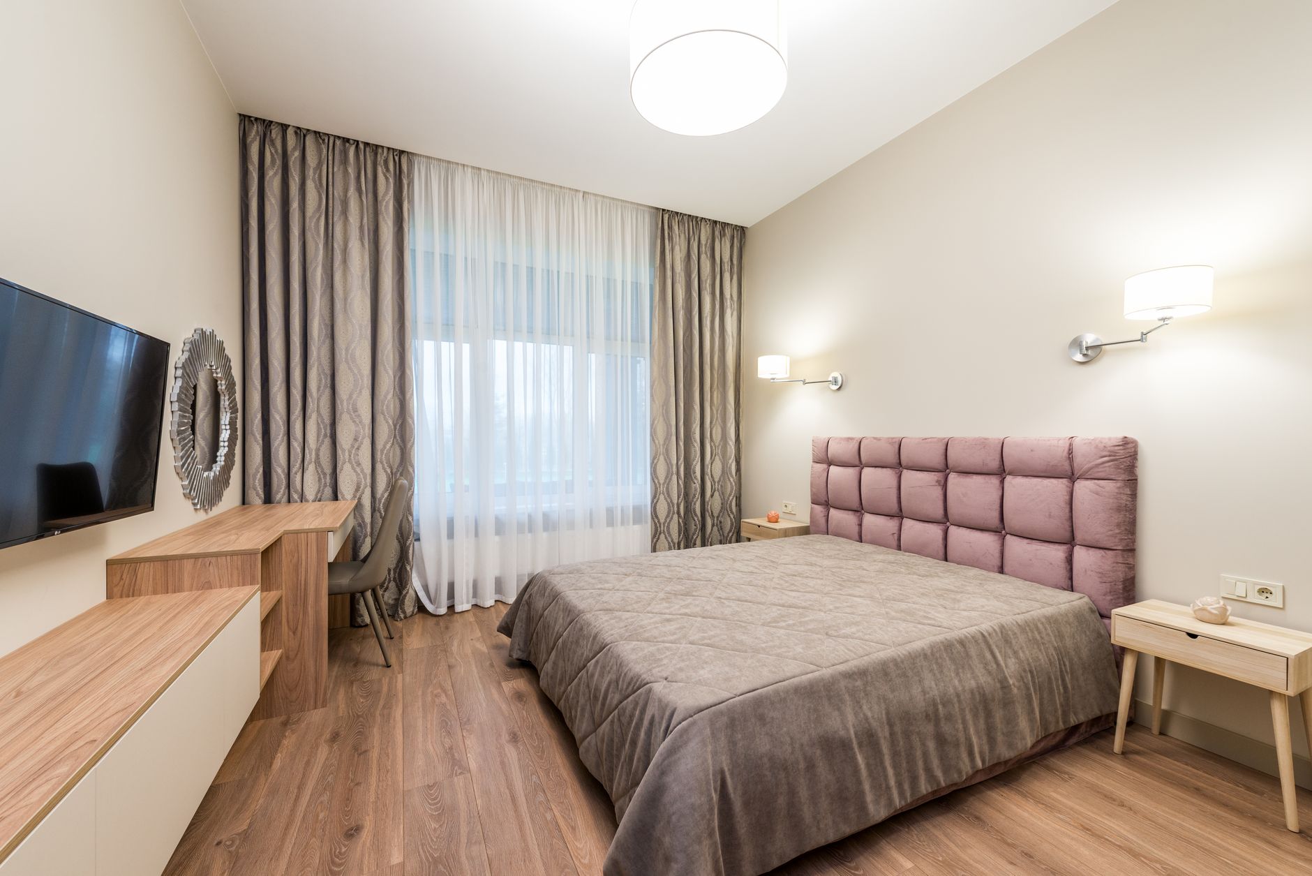 A hotel-style bedroom with a pink headboard