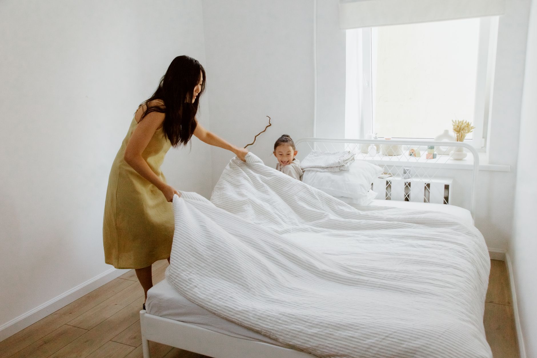 A woman making a bed with a child