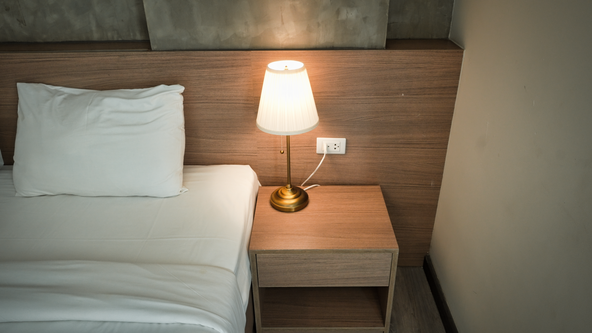 A bed beside a nightstand lamp and outlet