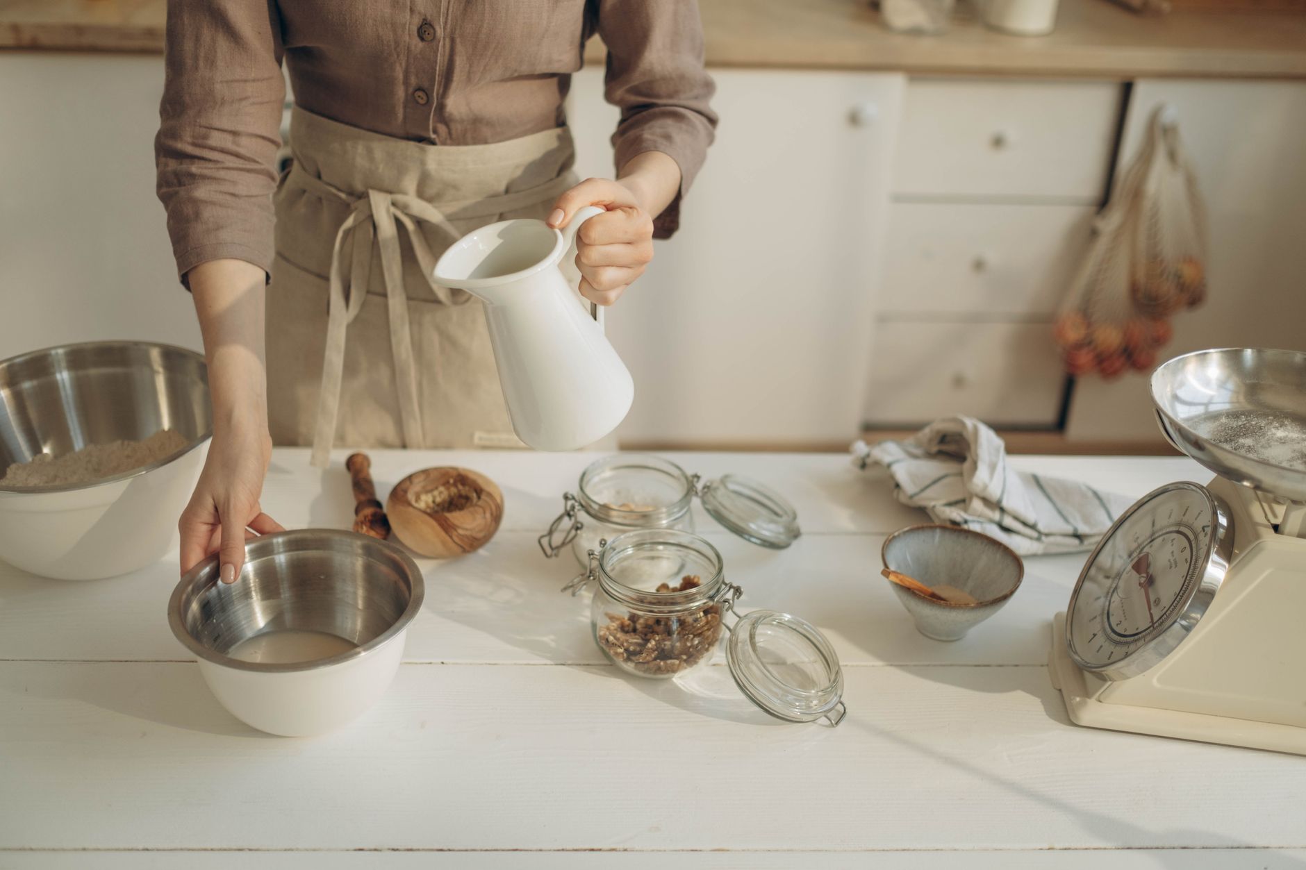 A baker pouring liquid into a bowl
