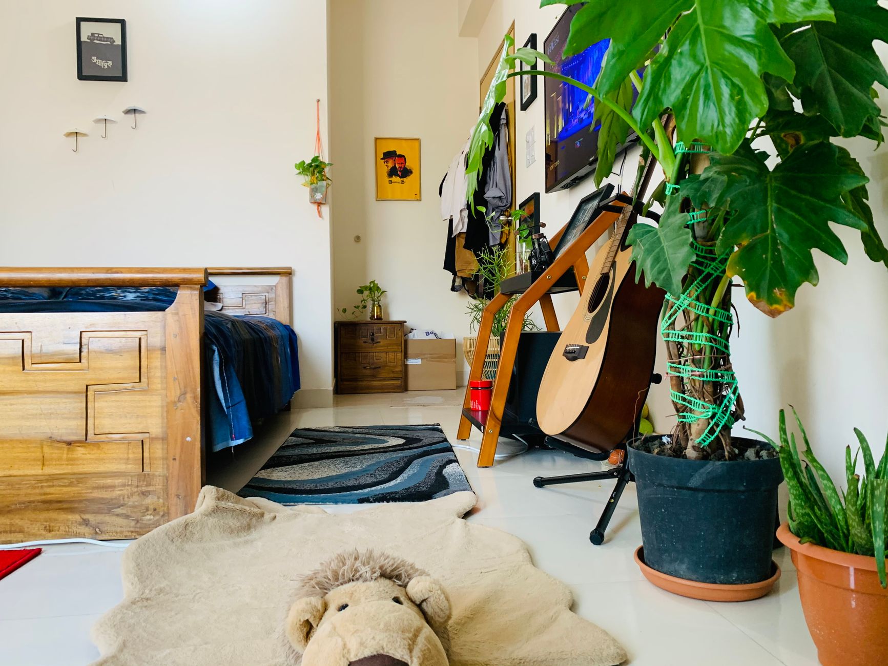 A small bedroom with plants and a guitar