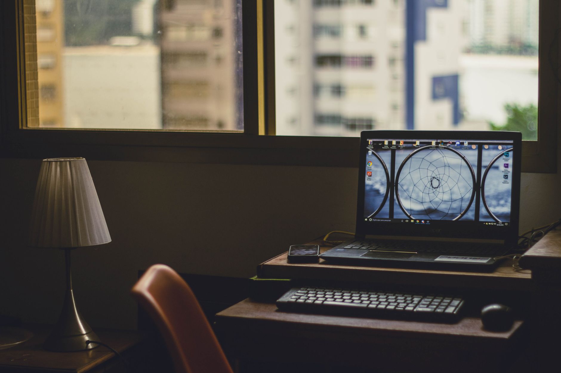 A laptop on a raised stand by a window at dusk