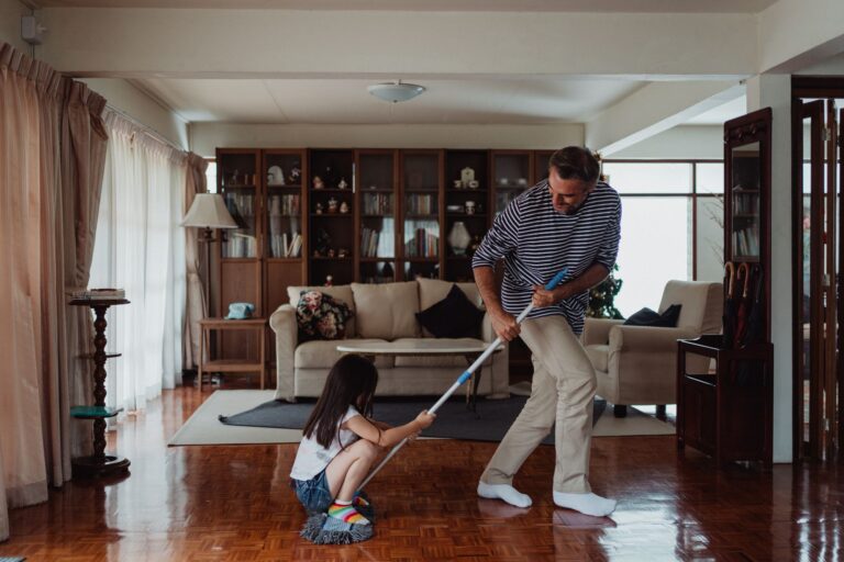 A parent and child mopping a wood floor