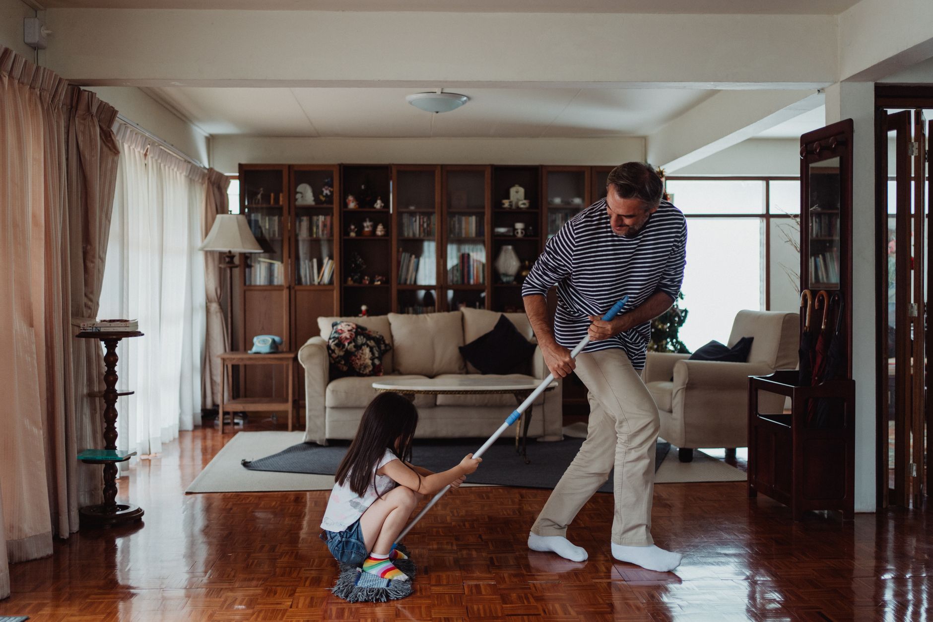 A parent and child mopping a wood floor