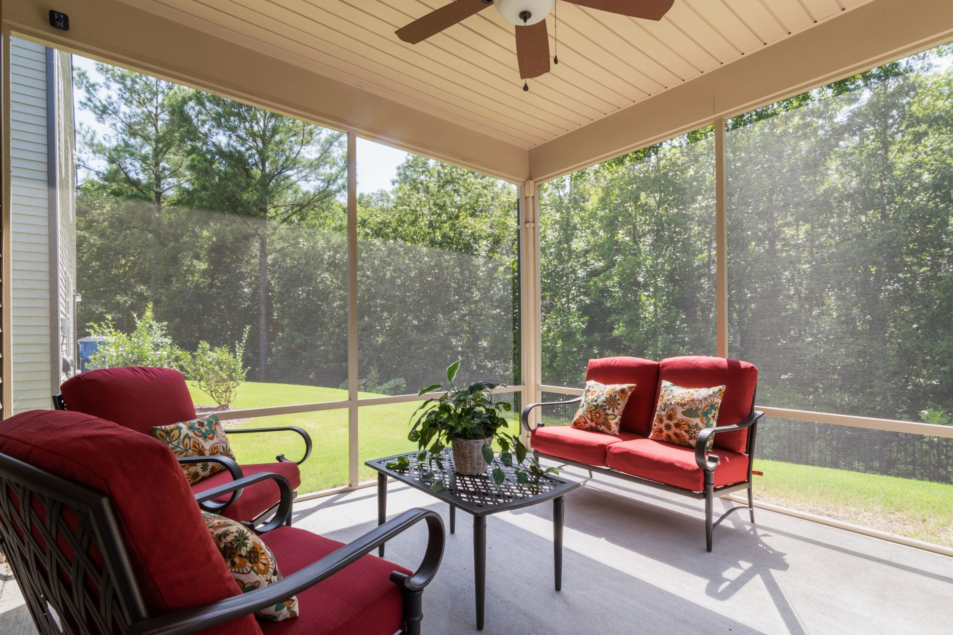 A screened porch with seating on a summer day