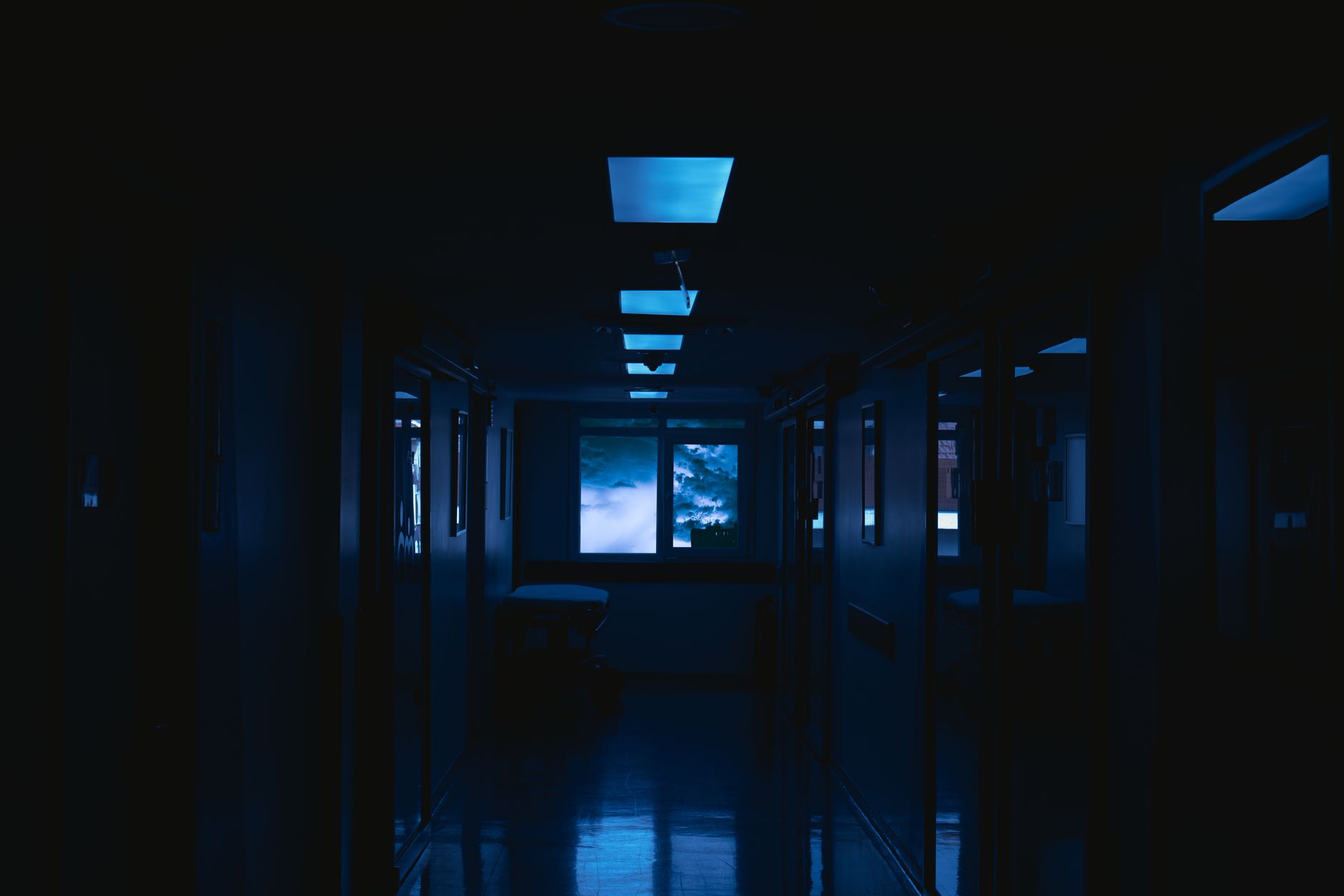 A long hallway in near darkness with faint lights