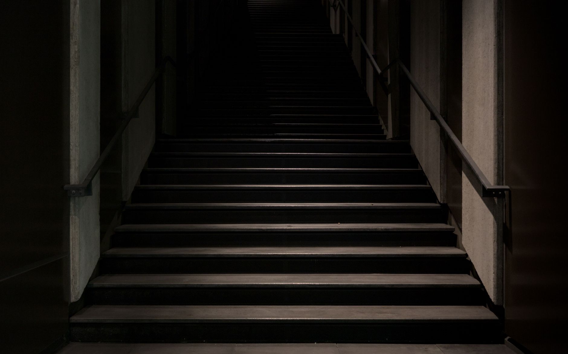 A dark staircase with handrails on both sides