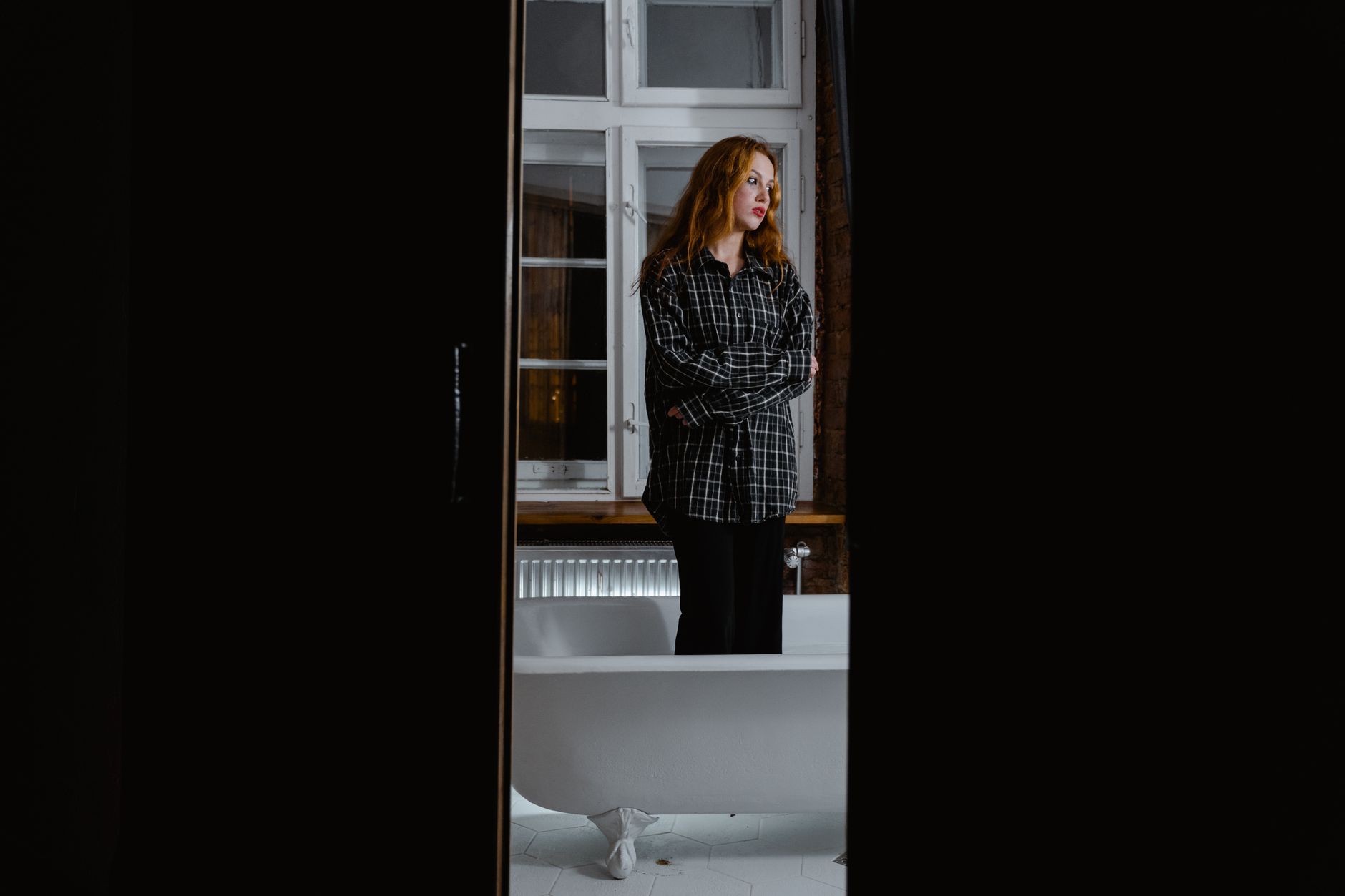 A woman standing in a dim bathroom doorway