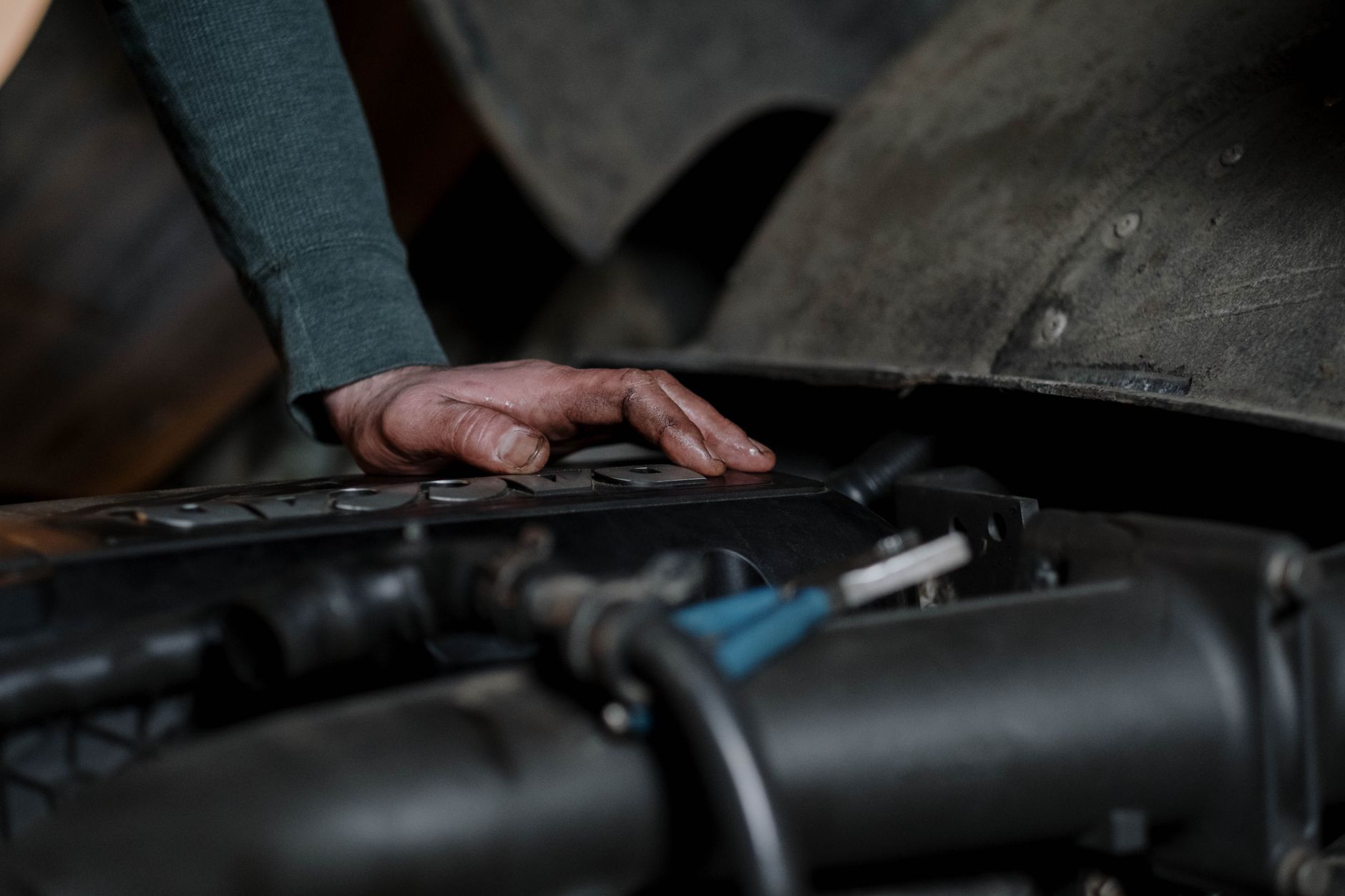 Best oil drain pan: a hand resting on a car engine