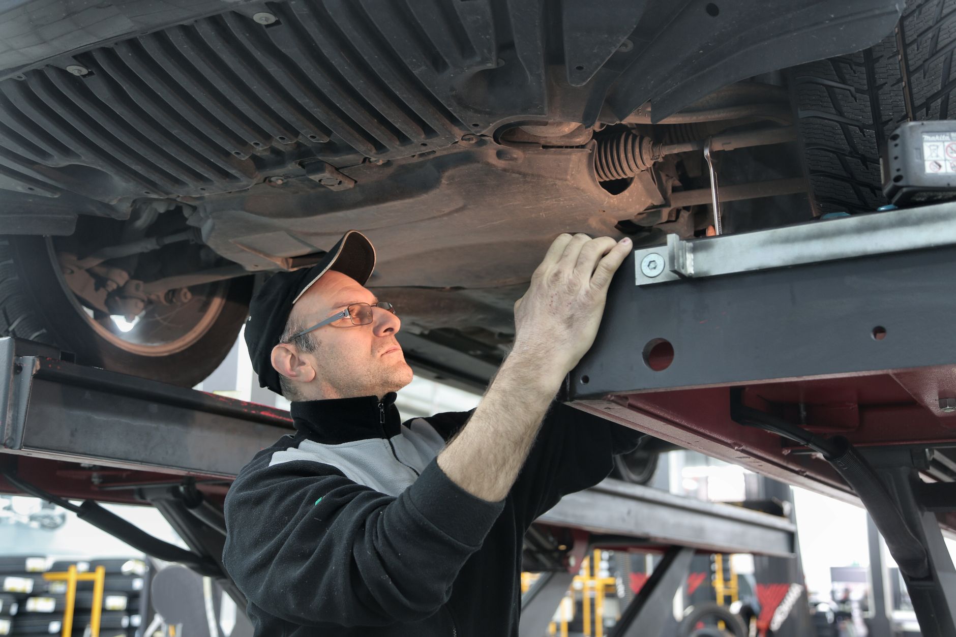 A mechanic inspecting the underside of a lifted car