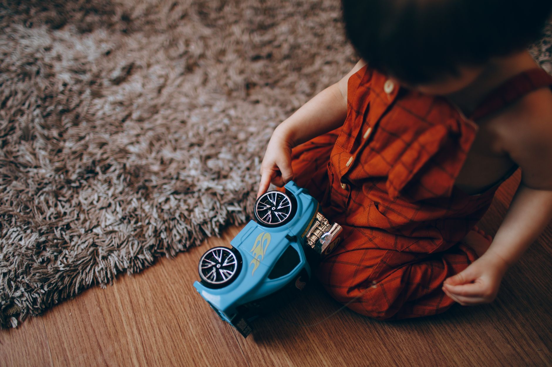 A toddler playing with a toy car on the floor