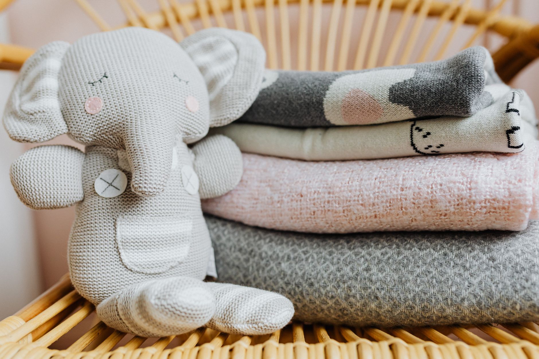 A stuffed toy elephant beside folded baby blankets