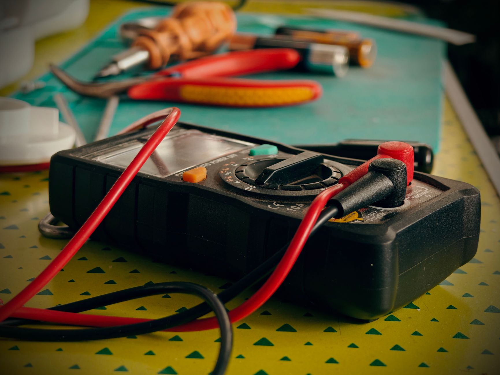 A digital multimeter with test leads on a workbench