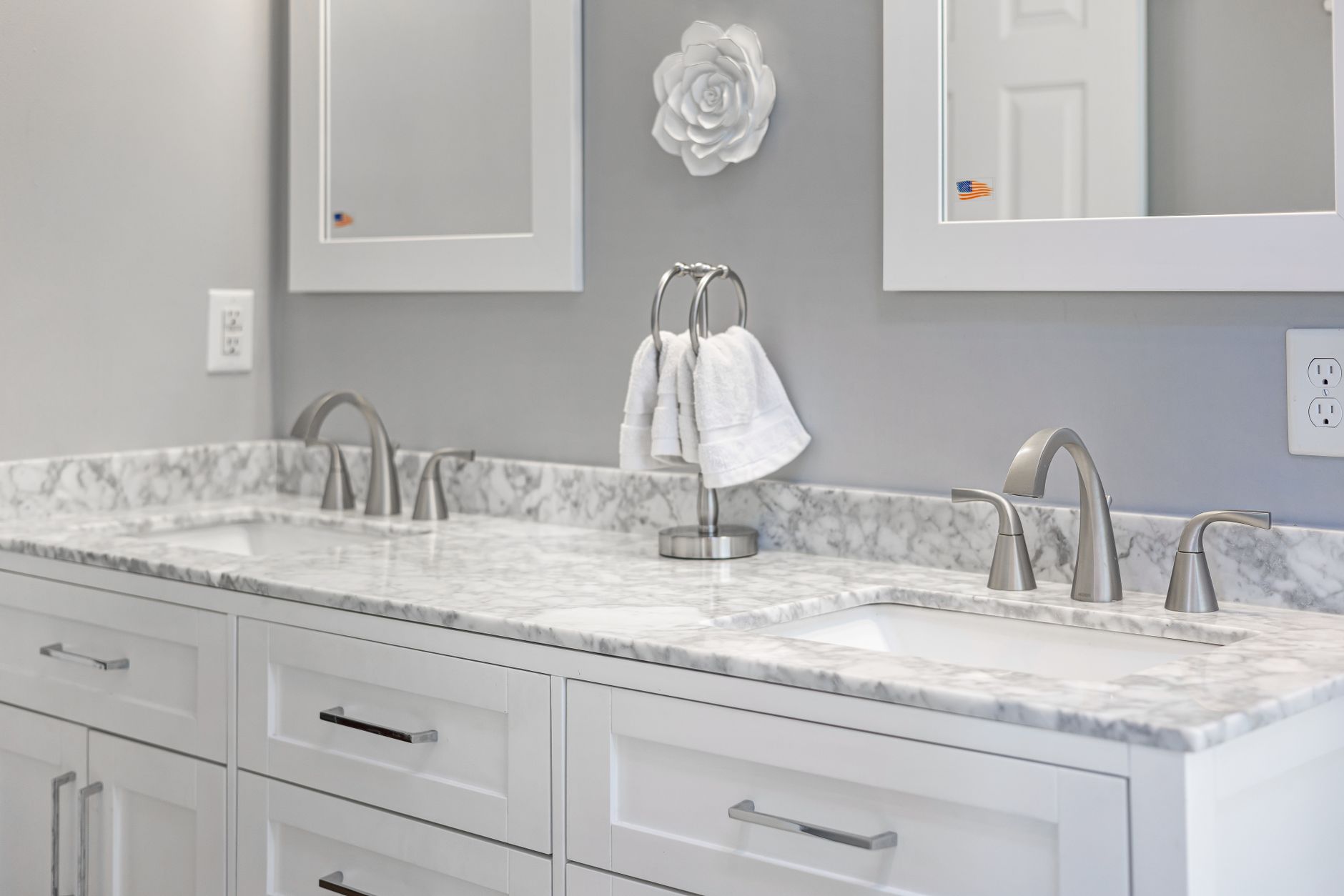 A bathroom vanity with two sinks and a wall outlet