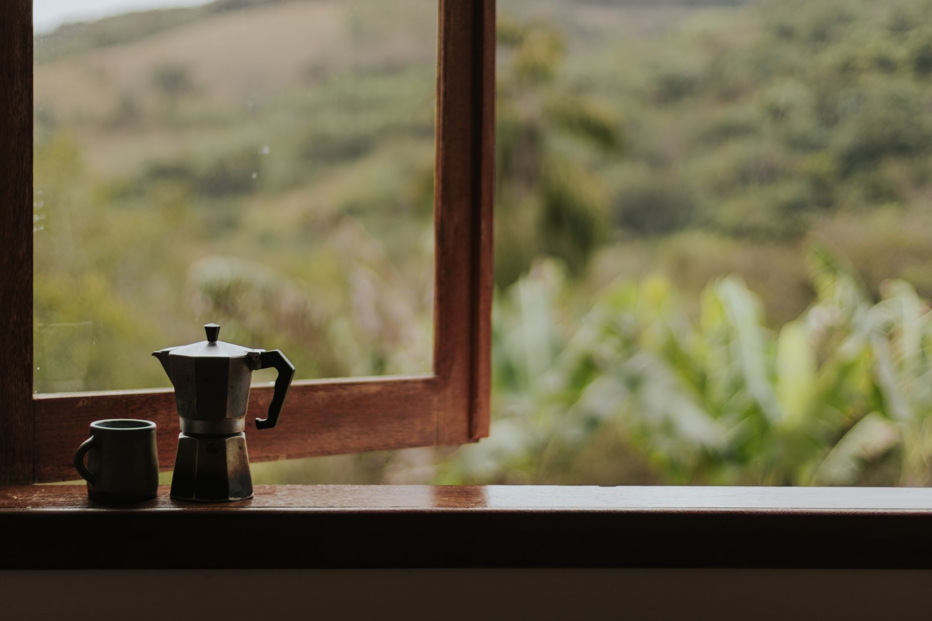 A coffee pot on a windowsill by an open window