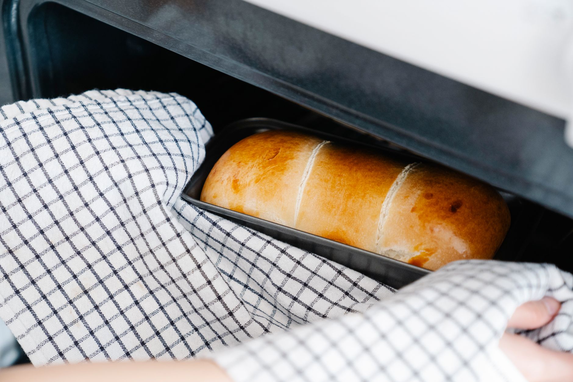 Best oven mitts: taking a loaf from the oven with a towel