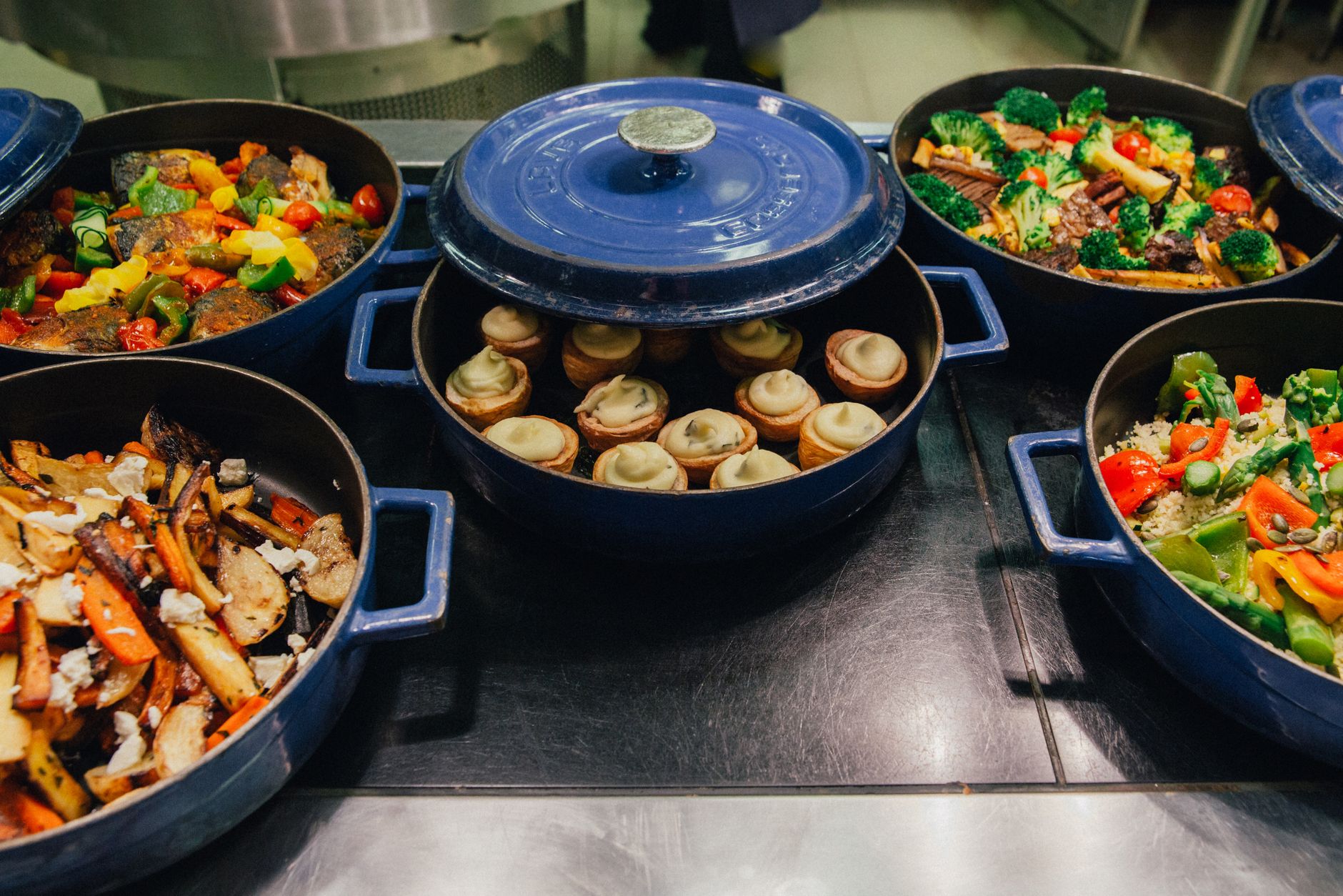 Blue cast-iron pots of cooked vegetables