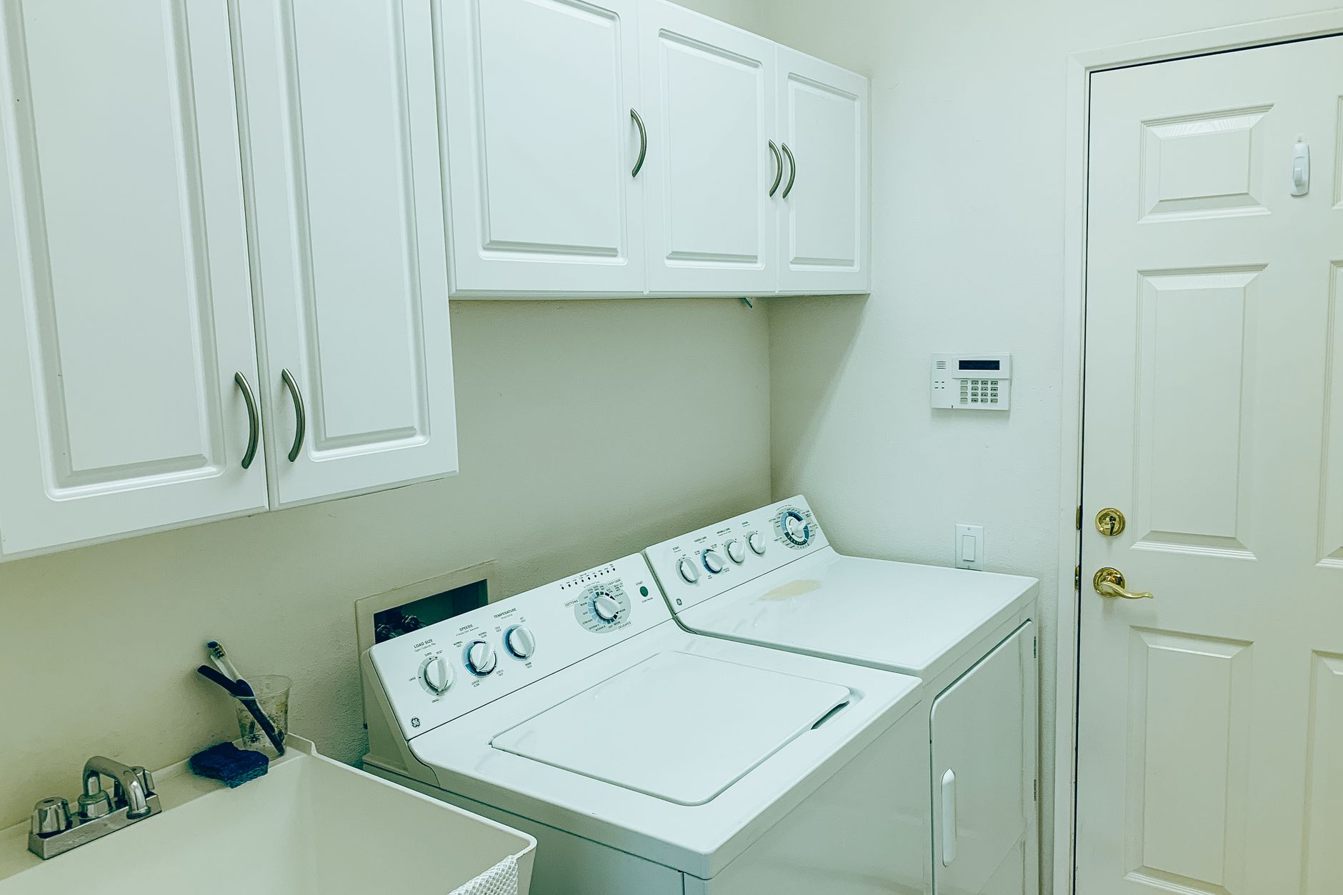 A laundry room with a washer, dryer and cabinets