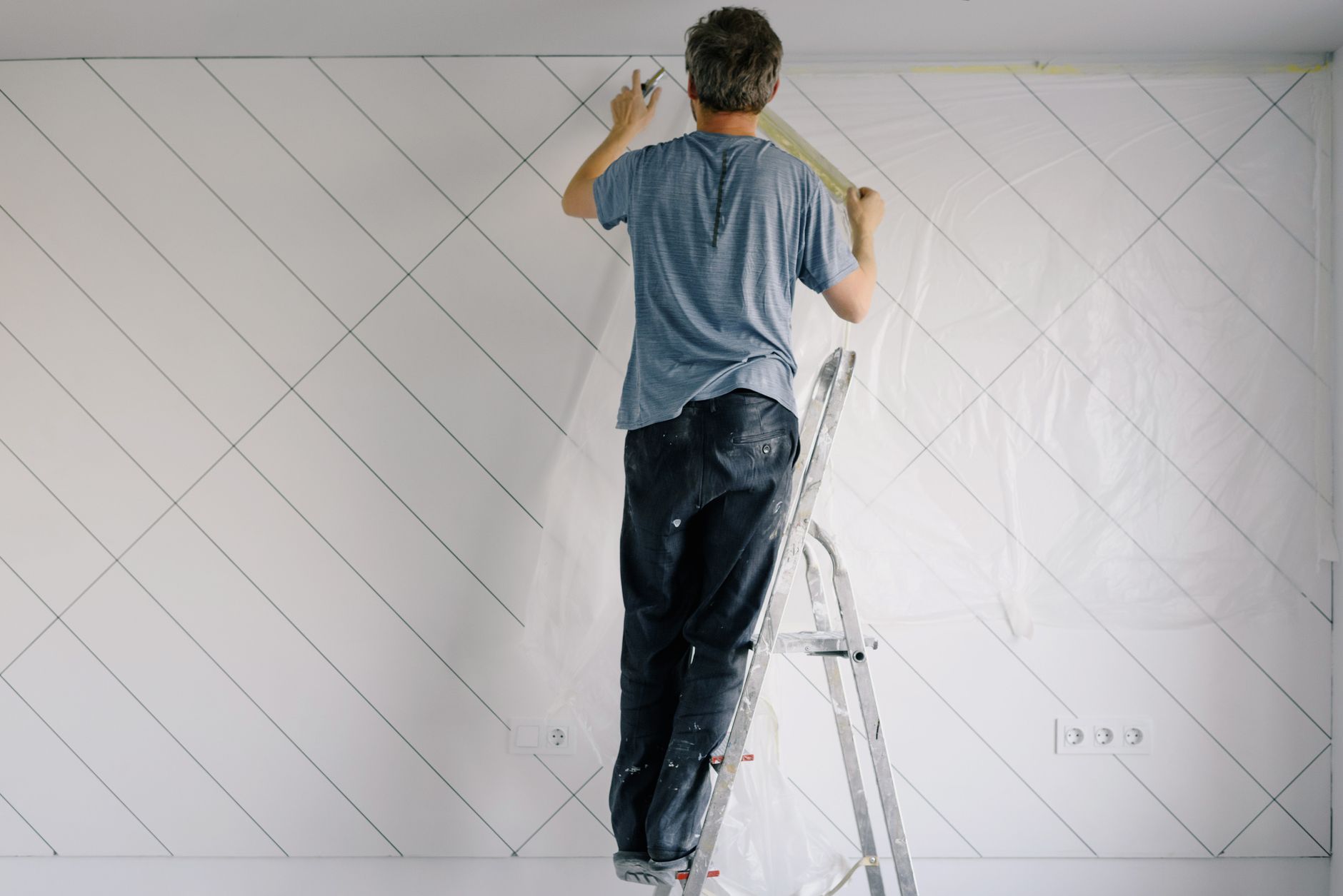 A painter on a ladder in an empty room