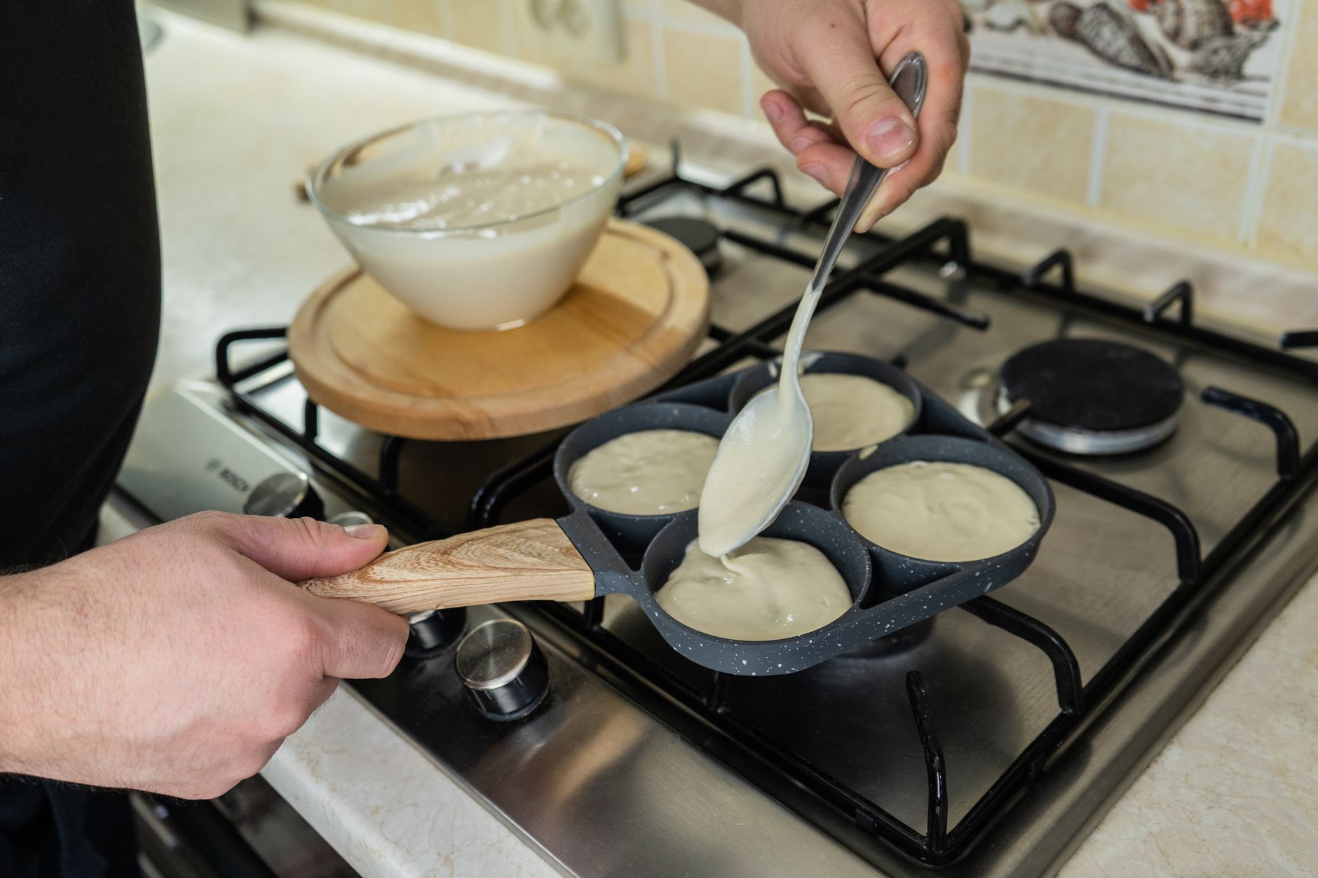 Pouring batter into a pancake pan on a gas stove