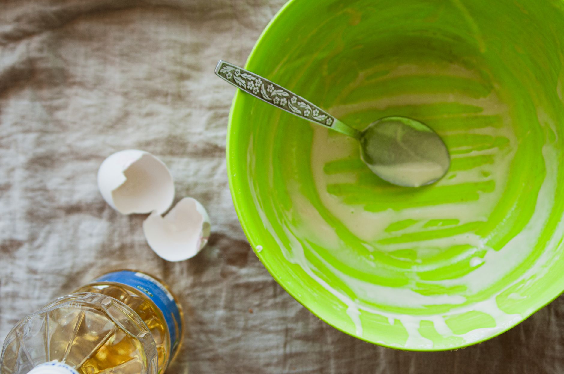 A green bowl of batter with cracked eggs