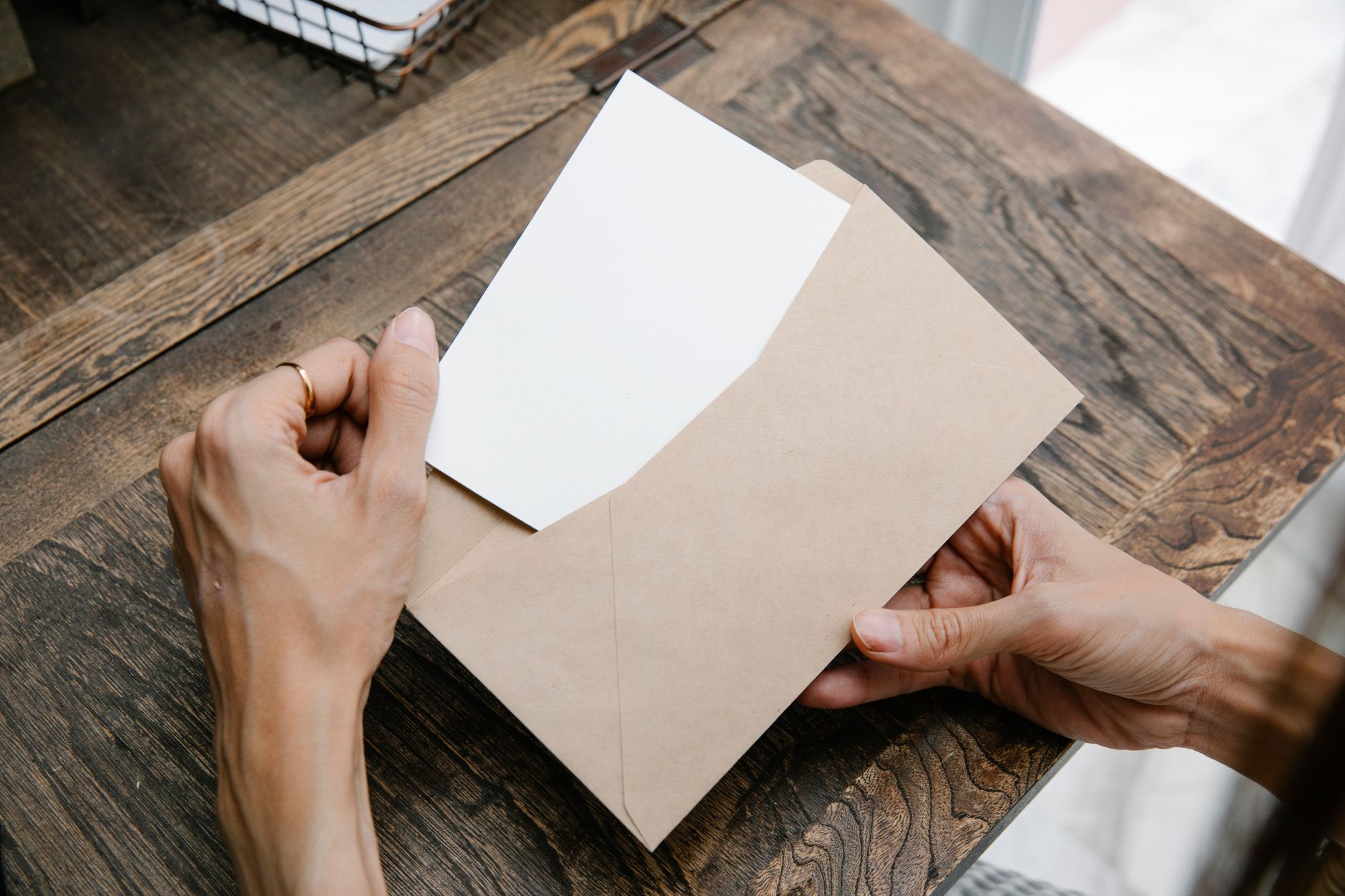 Hands opening an envelope at a table