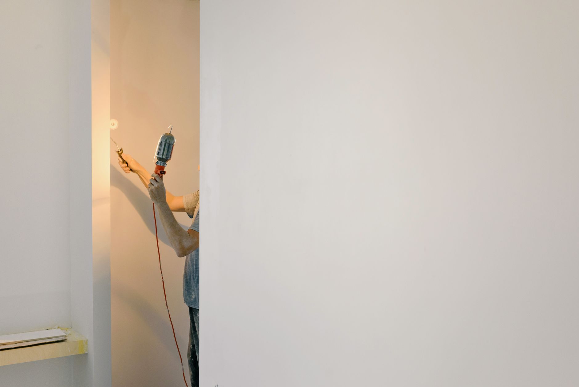 A person using a cordless drill on a wall