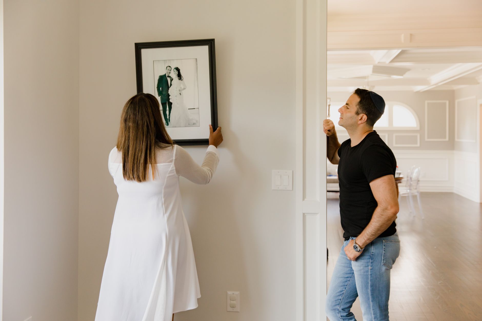 A person hanging a picture frame on a wall