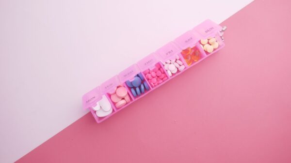 A pink weekly pill organizer filled with tablets
