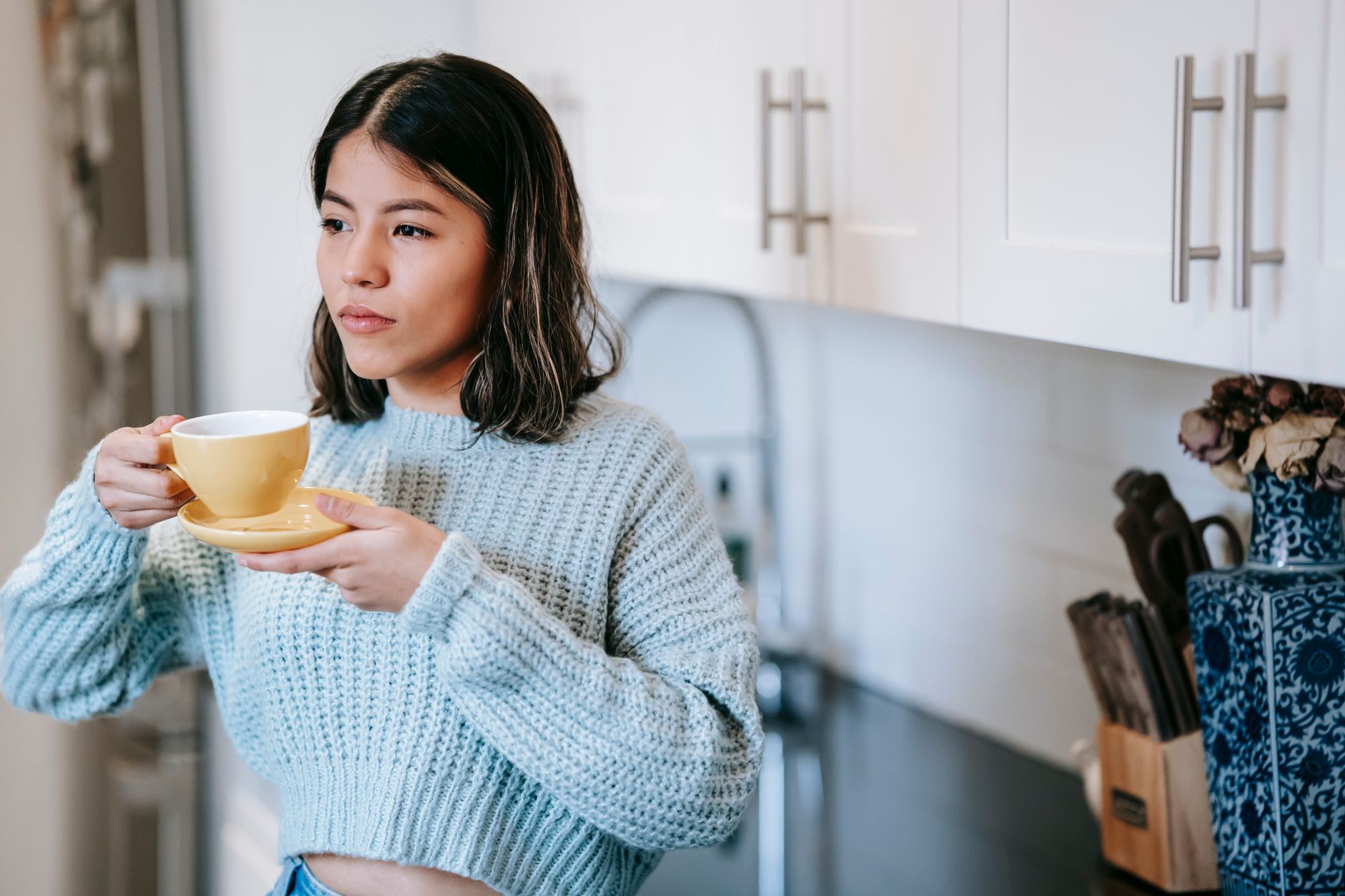 A woman holding a cup of tea in her kitchen
