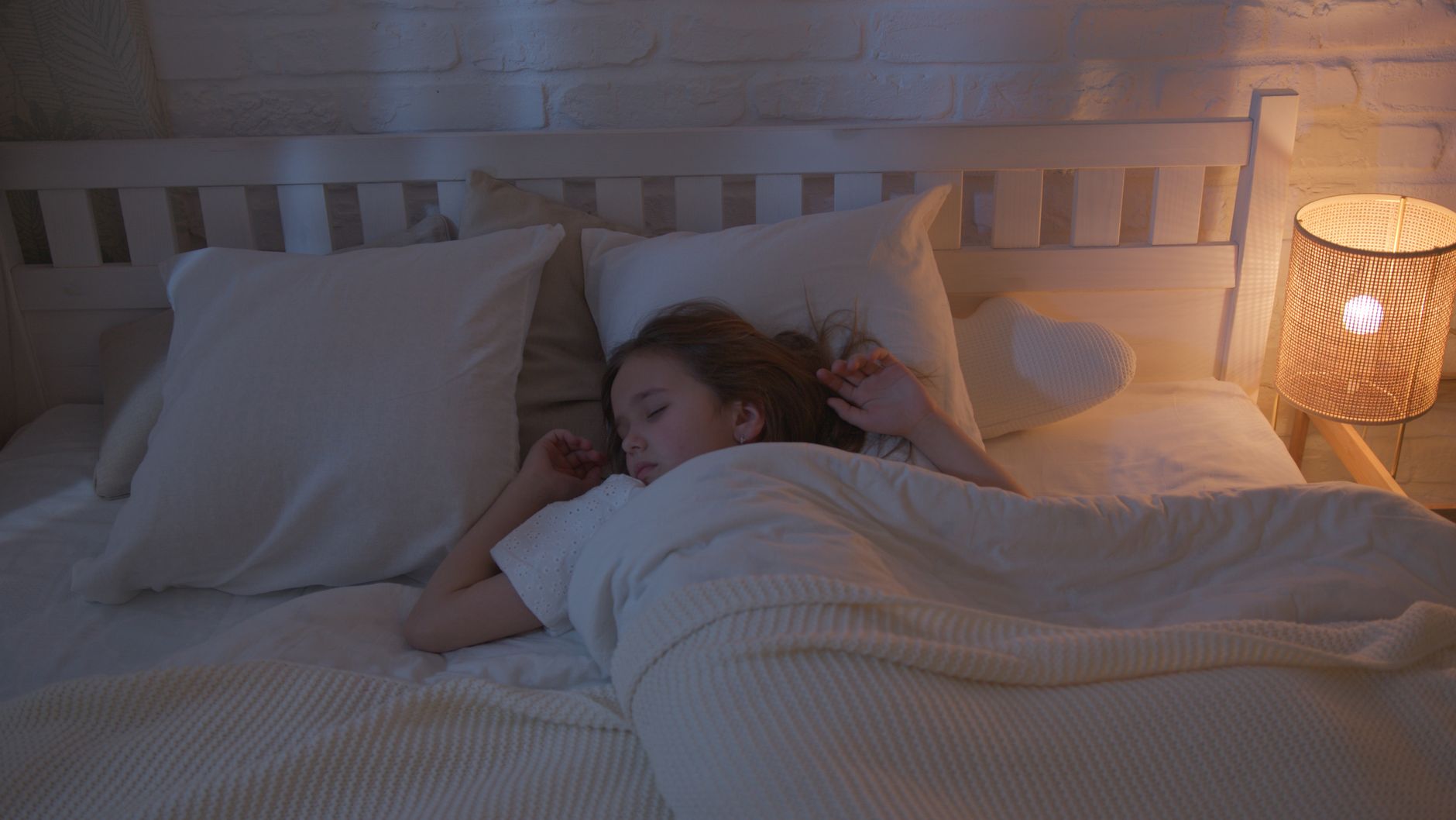 A bedroom lit by a bedside lamp at night