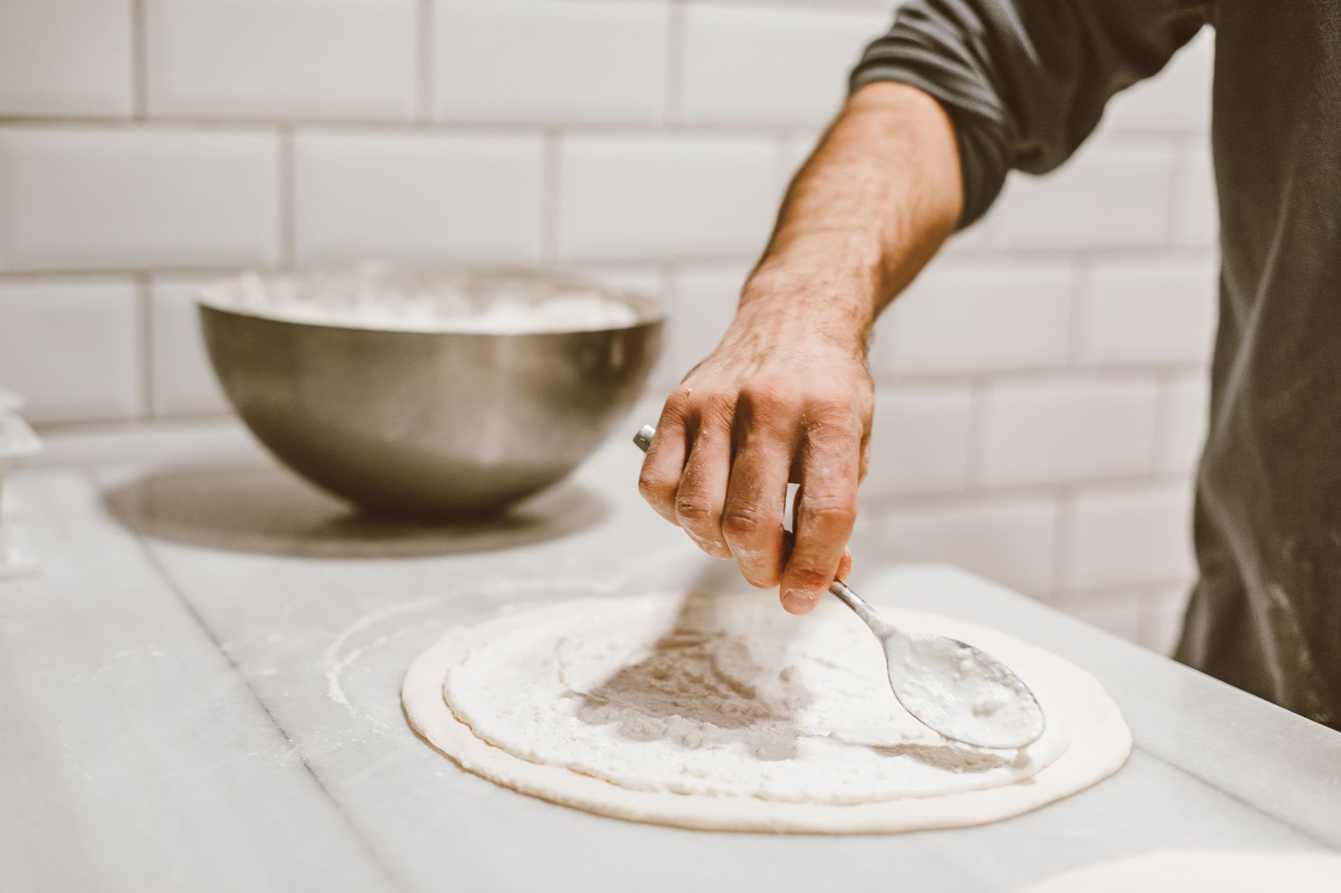 Pizza dough being prepared in a kitchen