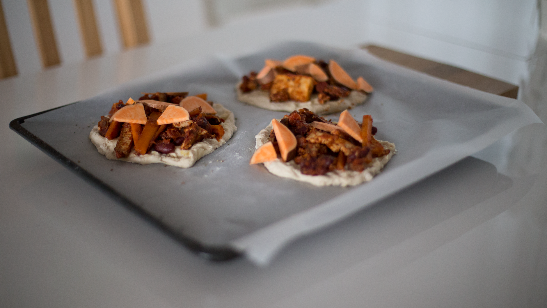 Small flatbread pizzas on a baking tray