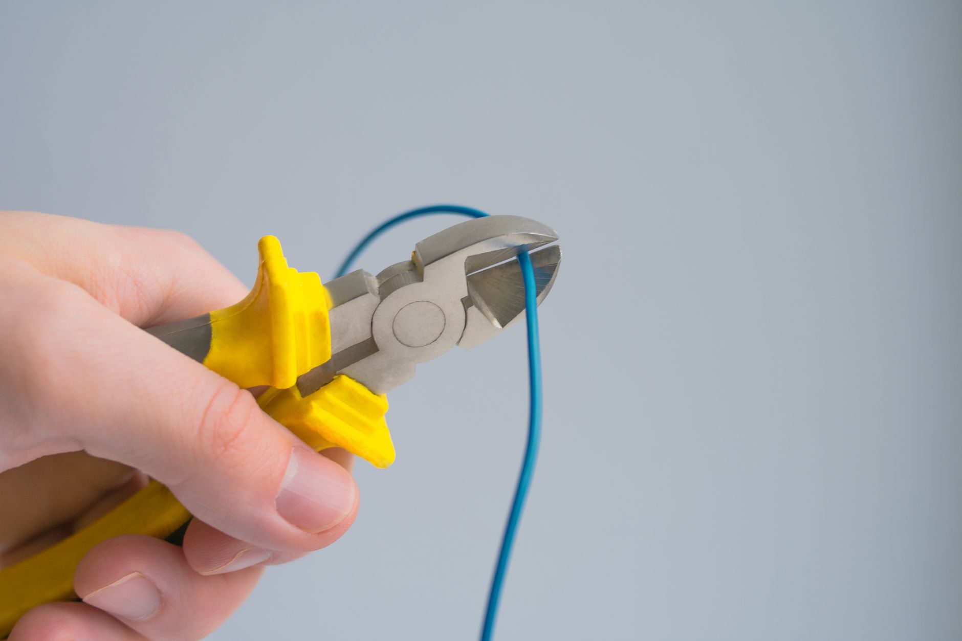 Hands using pliers to cut a piece of wire
