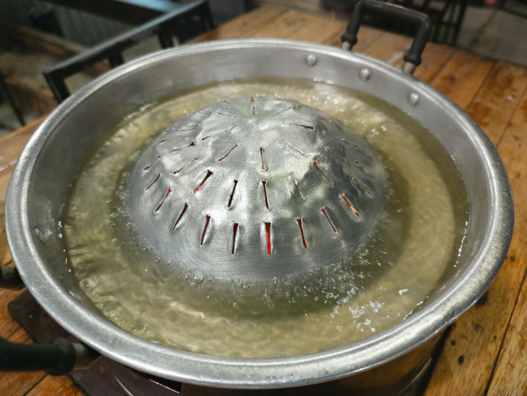 A large aluminum pot on a table