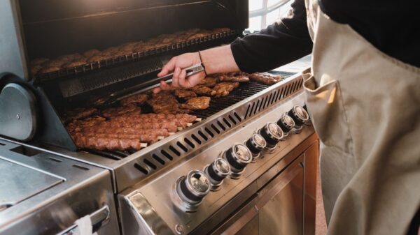 Sausages cooking on a stainless steel gas grill