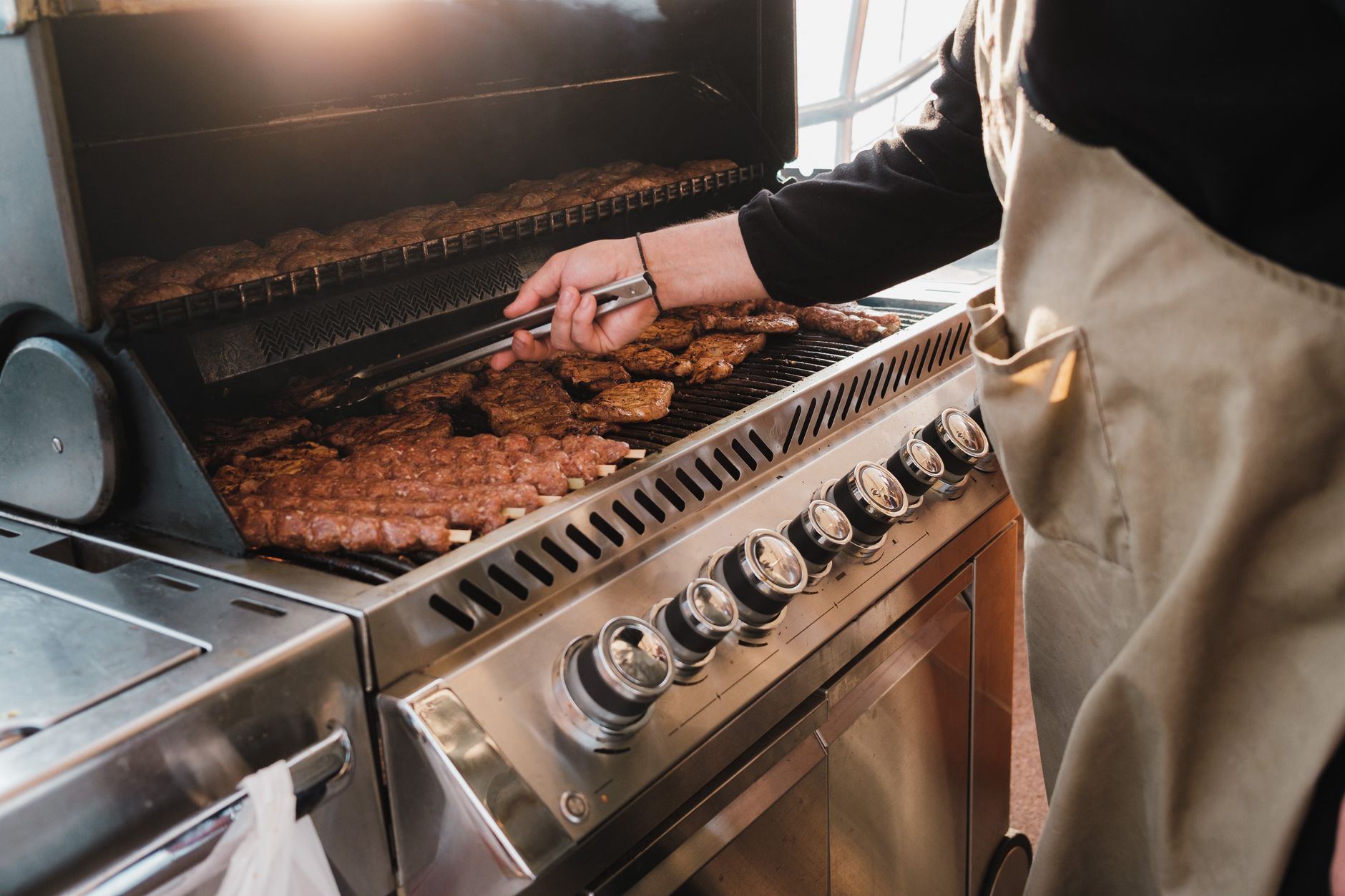 Sausages cooking on a stainless steel gas grill