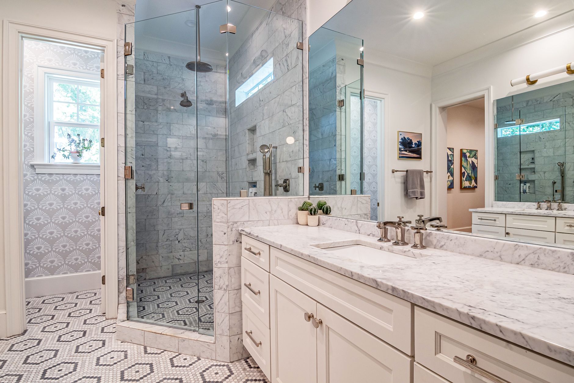 A bathroom with a glass shower and long vanity