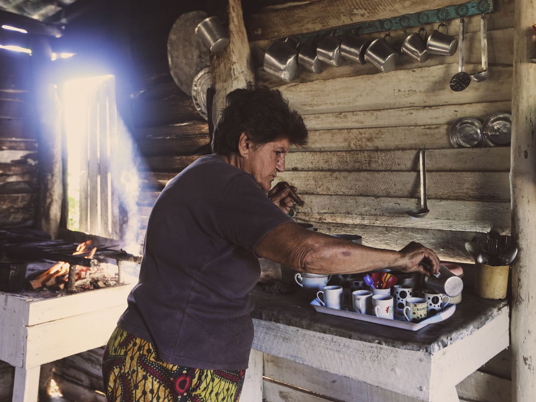 A woman setting out cups in a rustic kitchen
