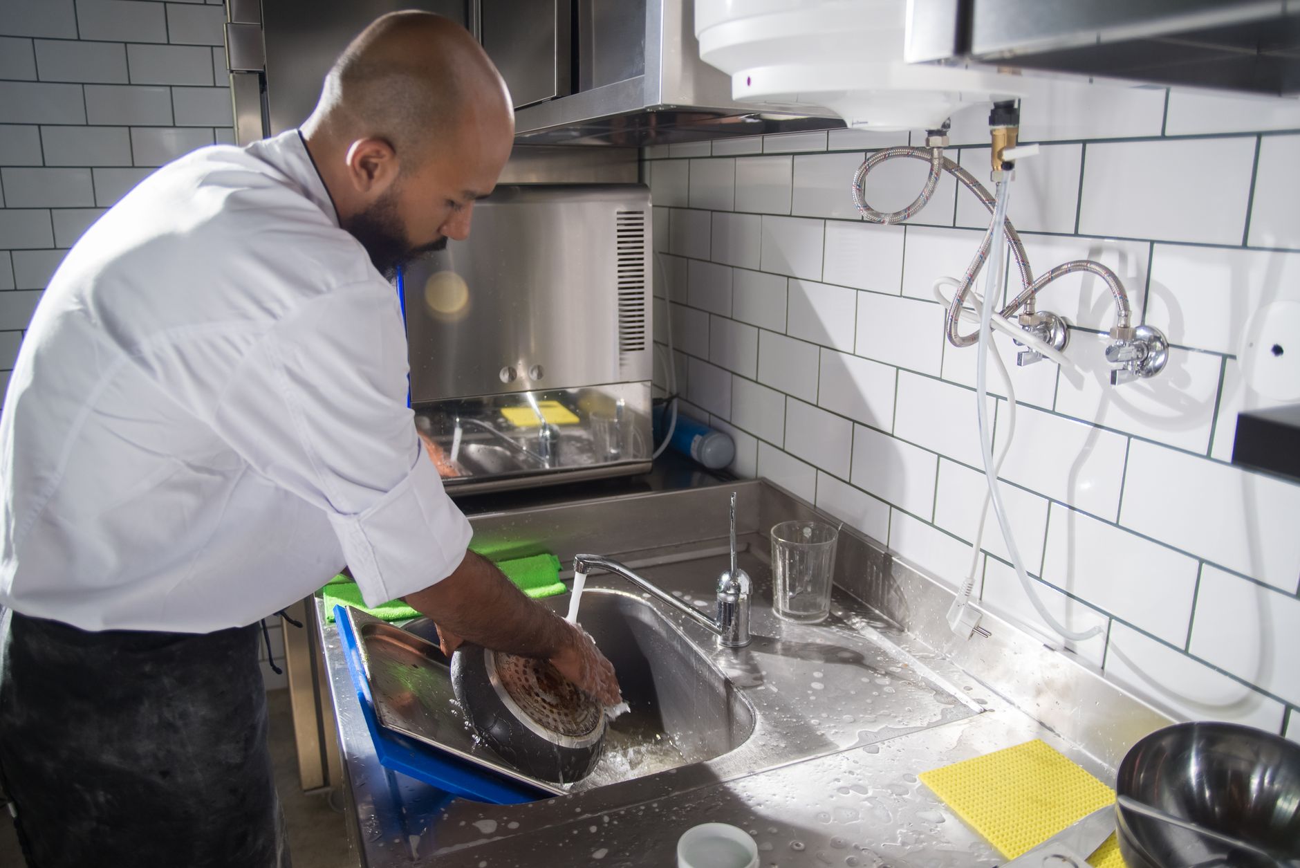 A cook washing dishes in a commercial kitchen