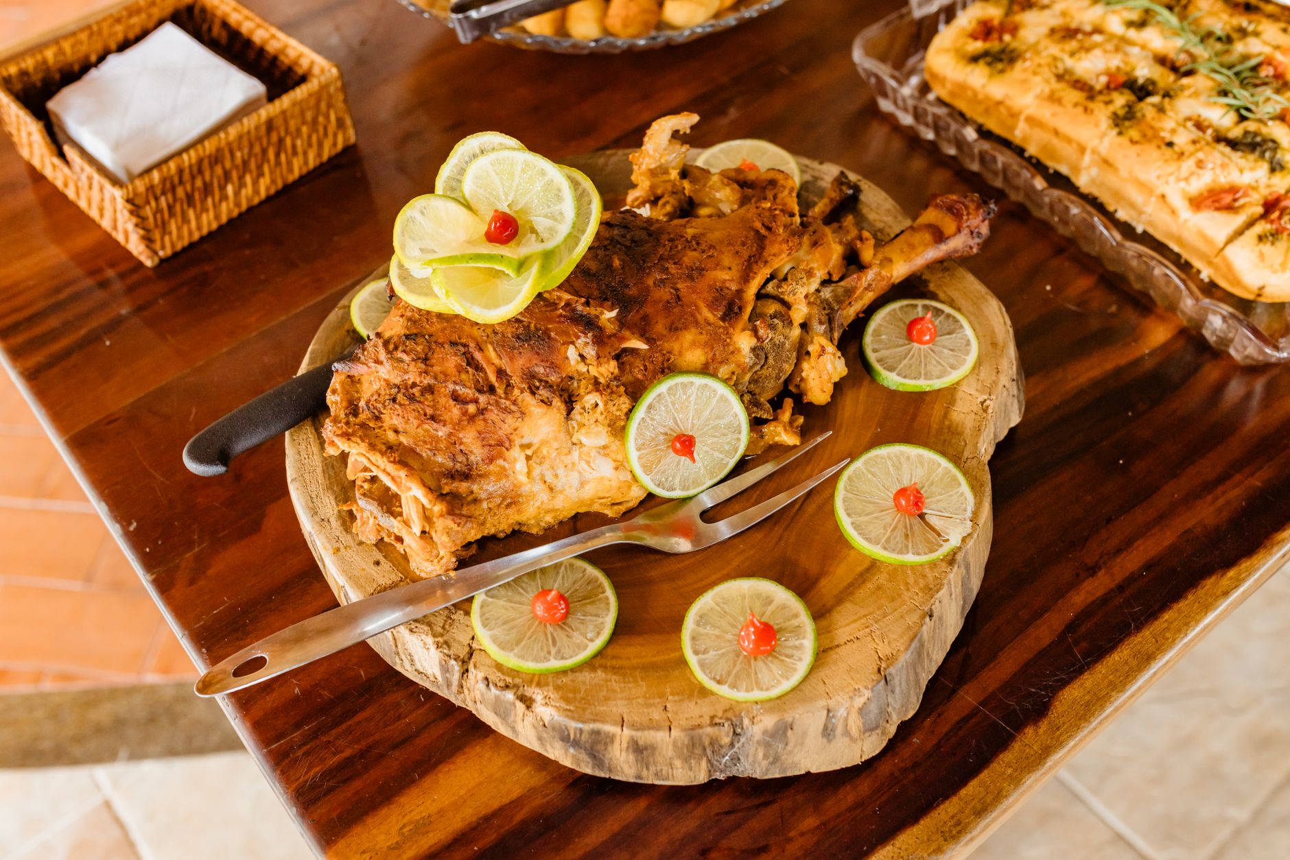 A roast bird on a wooden board with limes