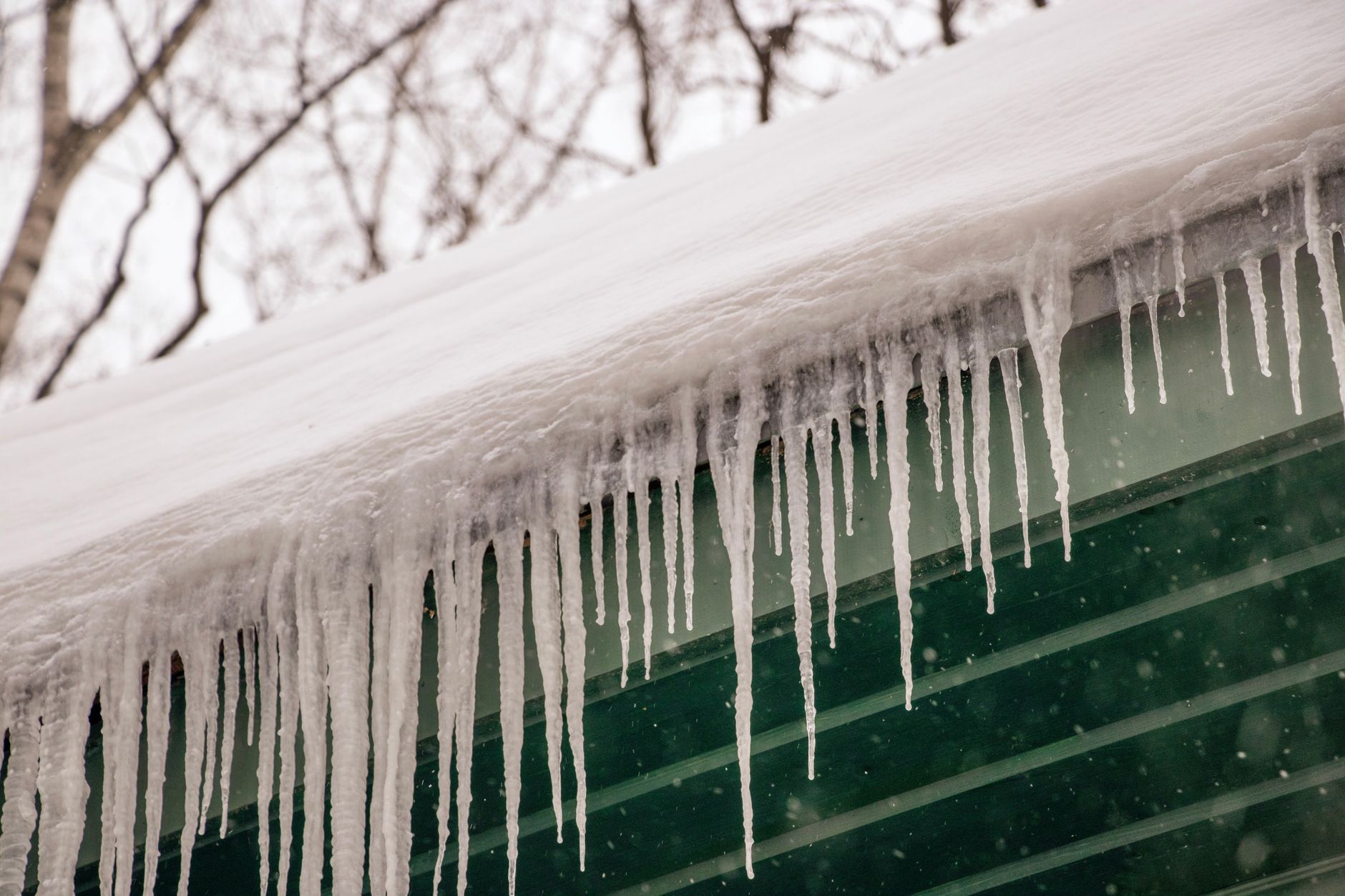 Best roof de-icing cable: icicles hanging from a snowy roof edge