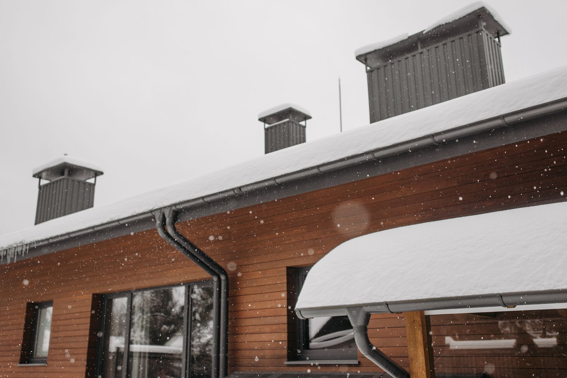 Snow on the roof and gutters of a wood-sided house