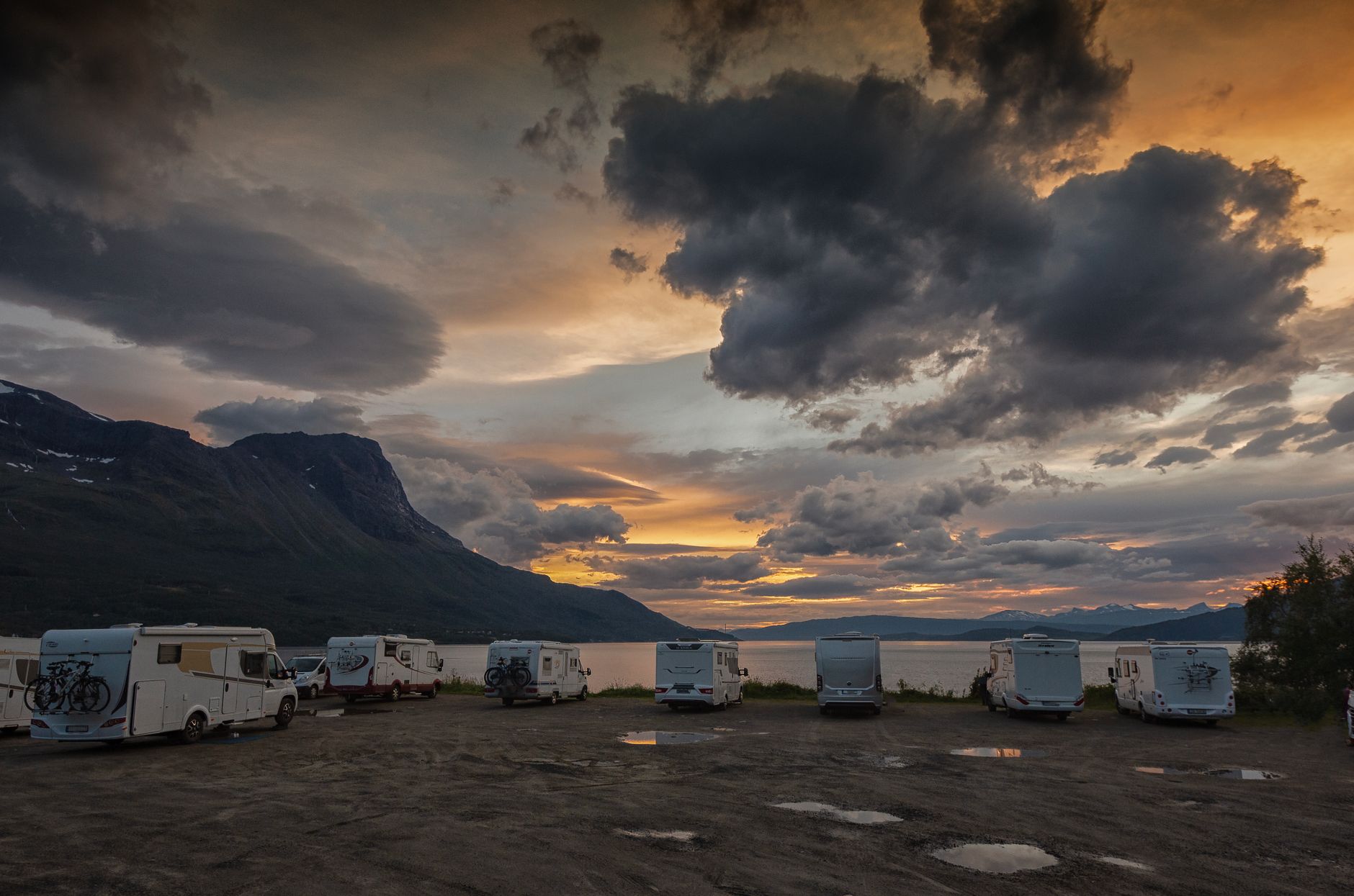 Motorhomes parked at a campground under storm clouds