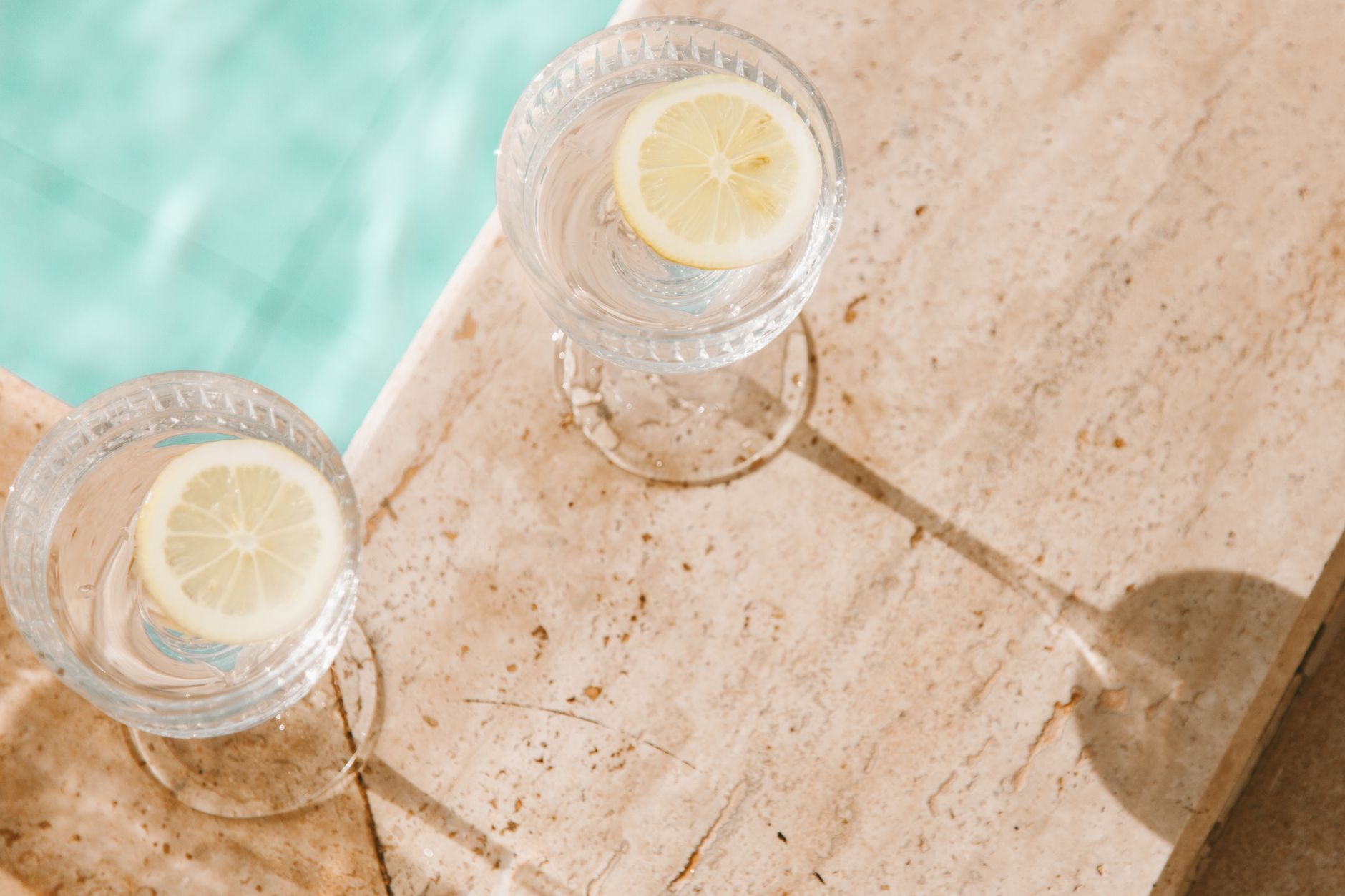 Glasses of water with lemon by a pool