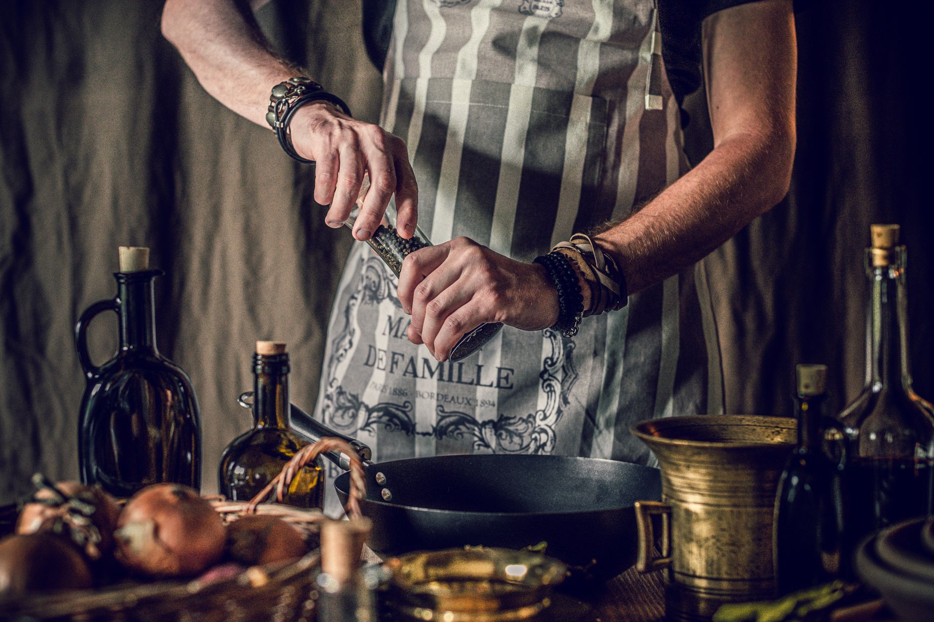 A cook grinding pepper over a pan