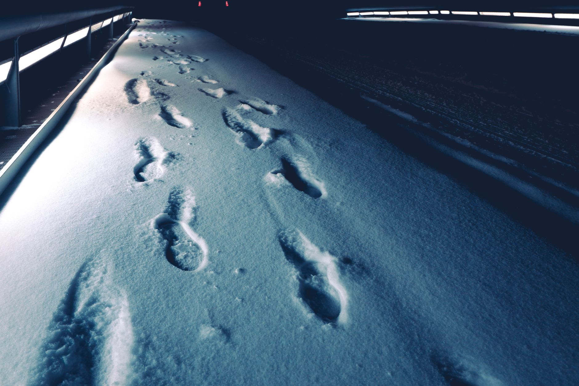 Footprints in fresh snow on a path at night