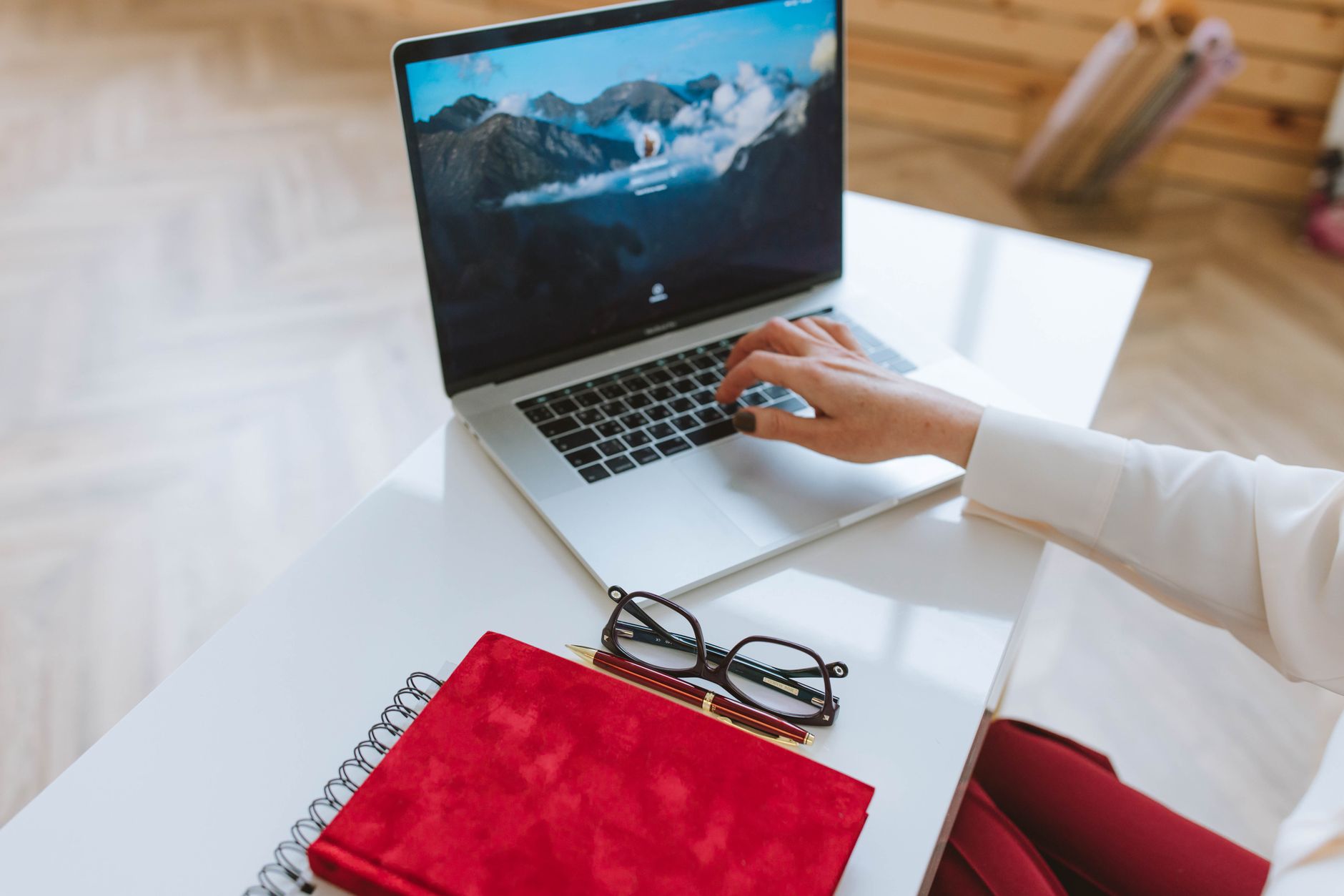 A person working at a laptop at a home desk