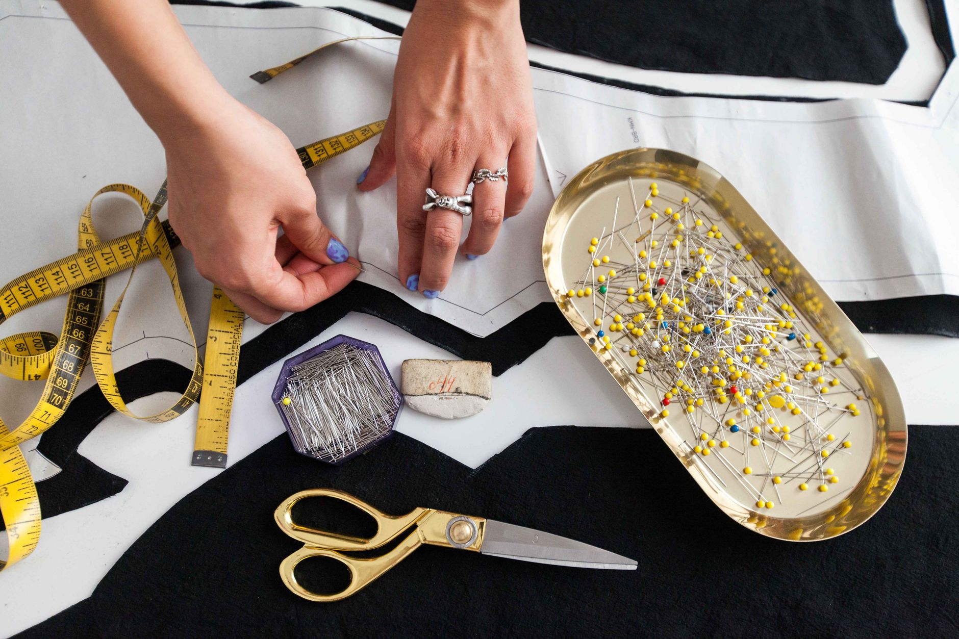 Pins, scissors and a tape measure on fabric